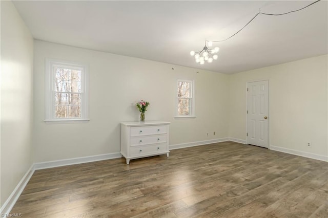 empty room with hardwood / wood-style floors and a notable chandelier