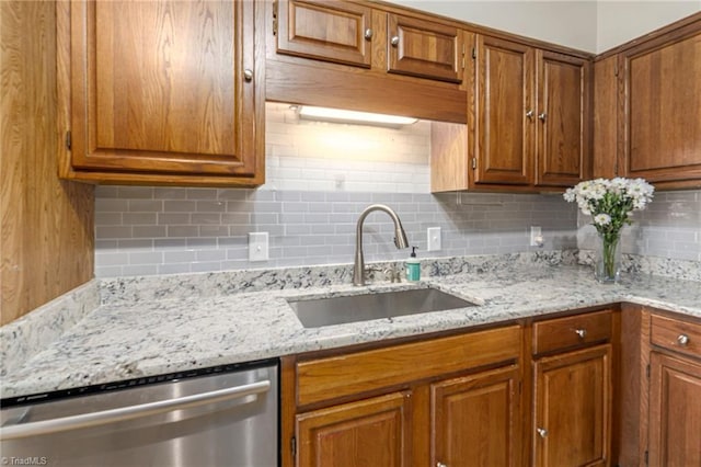 kitchen featuring light stone counters, tasteful backsplash, stainless steel dishwasher, and sink