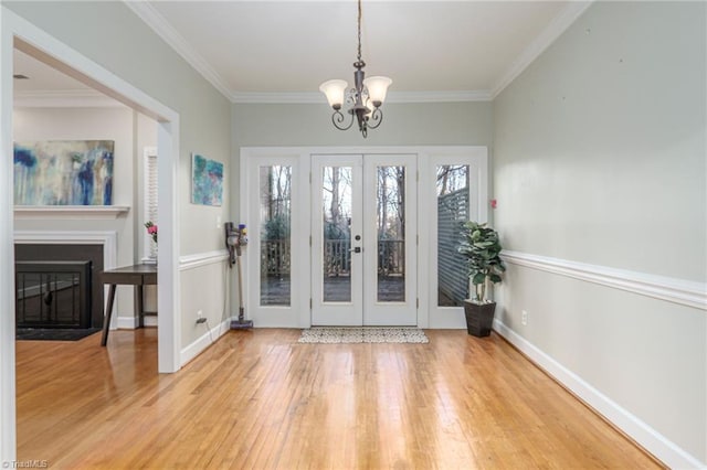 doorway featuring french doors, hardwood / wood-style flooring, an inviting chandelier, and crown molding