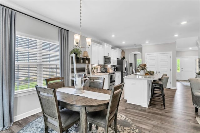 dining area featuring a chandelier, arched walkways, a wealth of natural light, and crown molding
