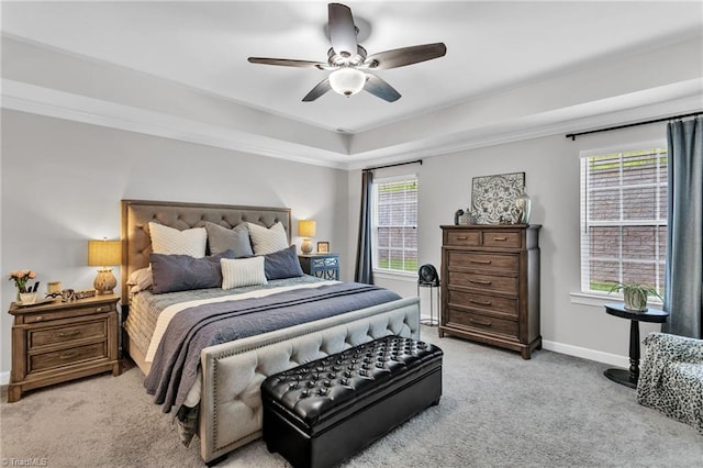 bedroom featuring light carpet, baseboards, a raised ceiling, a ceiling fan, and crown molding