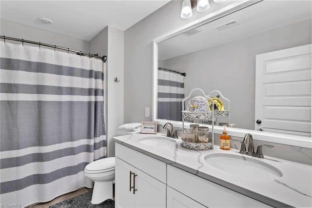 full bathroom with visible vents, toilet, double vanity, and a sink