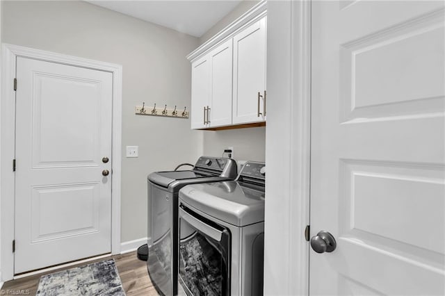 washroom featuring baseboards, cabinet space, light wood-style flooring, and independent washer and dryer
