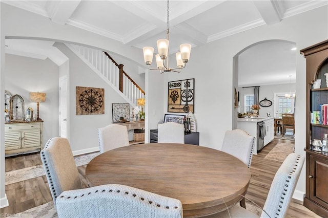 dining space featuring light wood-type flooring, arched walkways, coffered ceiling, and beamed ceiling