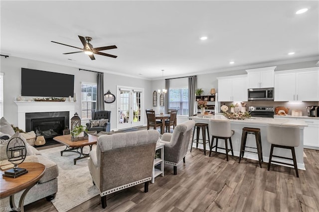 living room featuring ornamental molding, ceiling fan, and wood finished floors