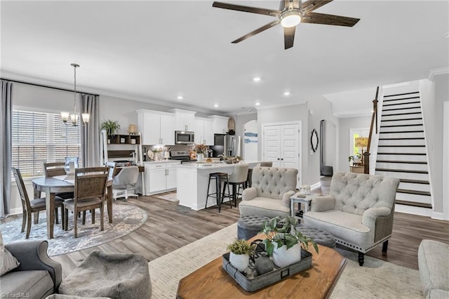 living area with recessed lighting, light wood finished floors, a wealth of natural light, and ceiling fan with notable chandelier