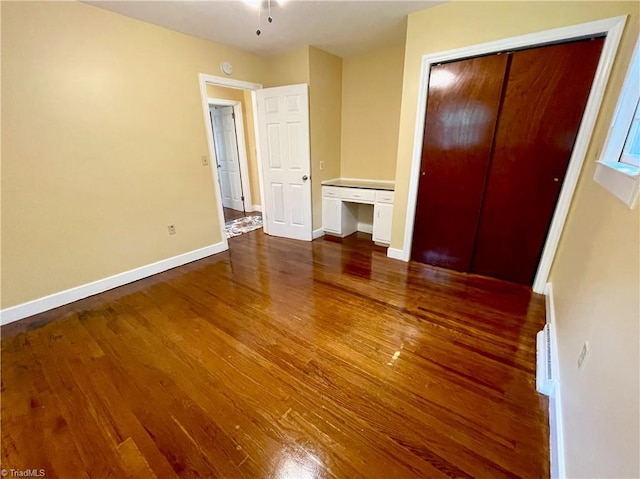 unfurnished bedroom with dark hardwood / wood-style floors and a closet