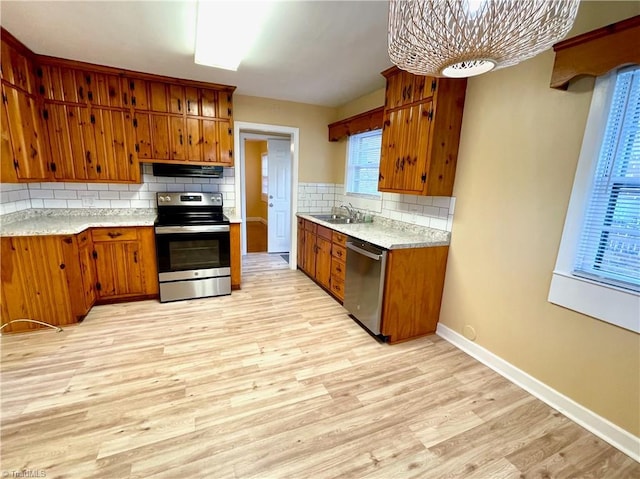 kitchen with appliances with stainless steel finishes, sink, decorative backsplash, and light hardwood / wood-style flooring