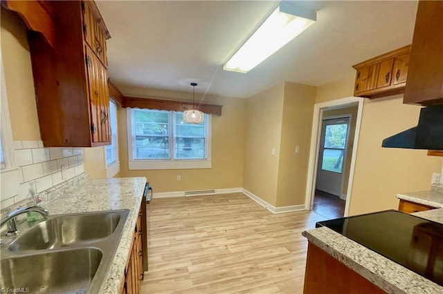 kitchen featuring tasteful backsplash, a healthy amount of sunlight, decorative light fixtures, and sink