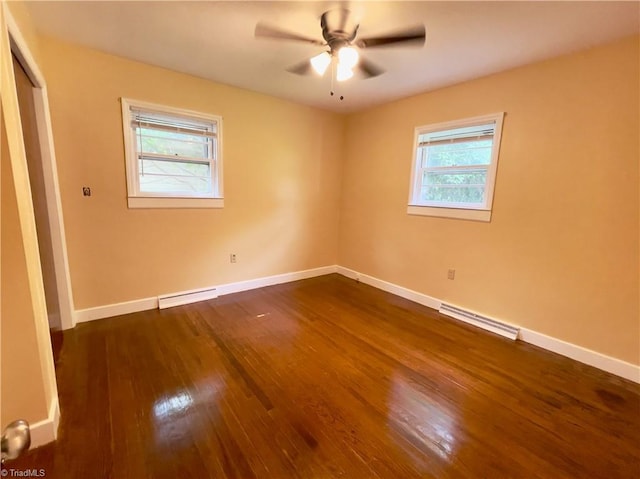 empty room featuring a baseboard heating unit, dark wood-type flooring, a wealth of natural light, and ceiling fan