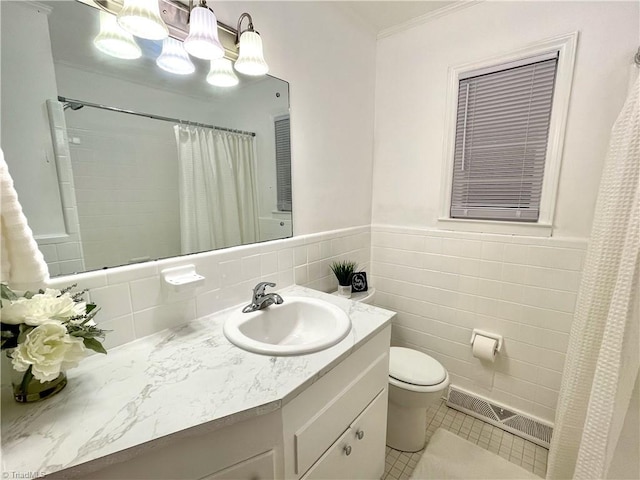 bathroom with tile walls, vanity, toilet, crown molding, and tile patterned floors