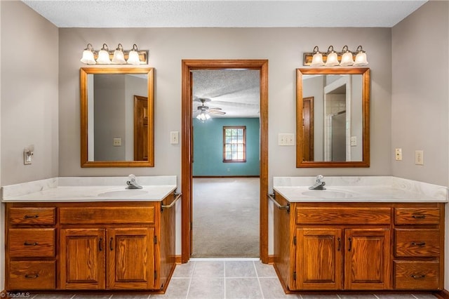 bathroom with two vanities, tile patterned floors, ceiling fan, and a textured ceiling