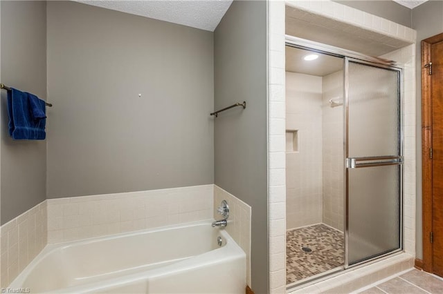bathroom featuring a stall shower, a bath, and tile patterned flooring