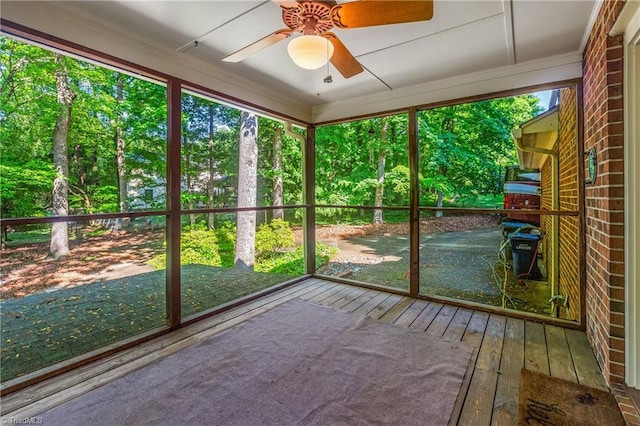 unfurnished sunroom with a ceiling fan and view of scattered trees
