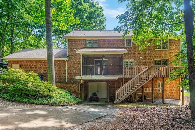 rear view of property with brick siding, stairway, ceiling fan, and driveway