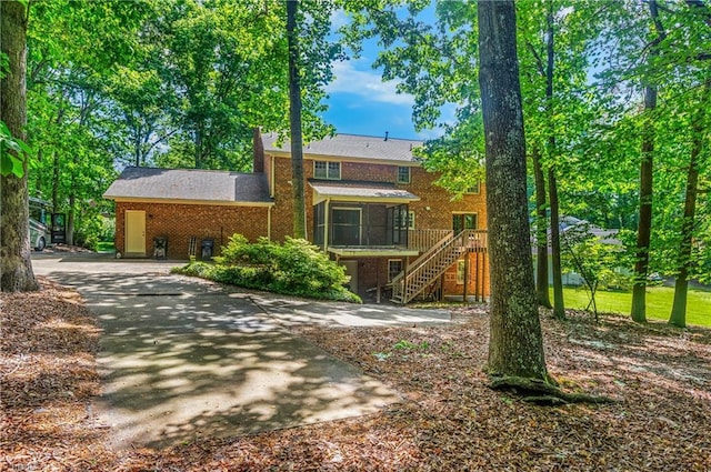 view of front of home featuring stairs, a wooden deck, and brick siding
