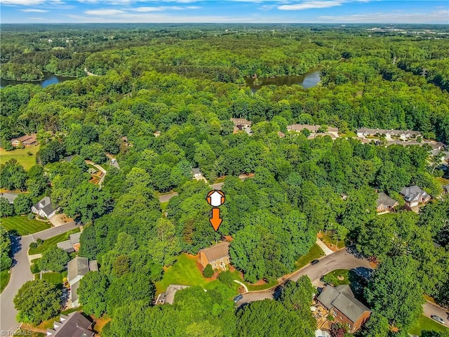 view of property location with a heavily wooded area and a nearby body of water