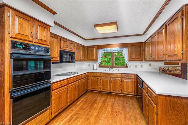 kitchen featuring black appliances, a textured ceiling, brown cabinets, ornamental molding, and light wood-style flooring
