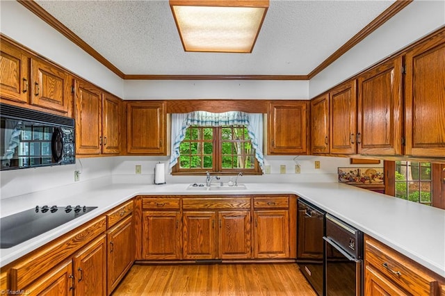 kitchen with black appliances, a sink, a textured ceiling, light wood-style flooring, and brown cabinets