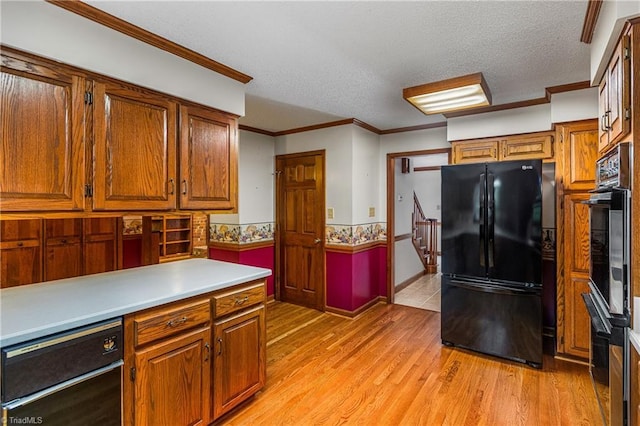 kitchen with black appliances, light wood-style flooring, brown cabinetry, light countertops, and a textured ceiling