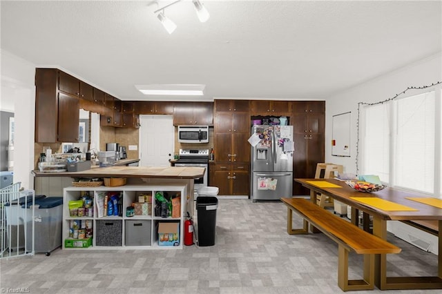 kitchen featuring appliances with stainless steel finishes, dark brown cabinetry, and kitchen peninsula