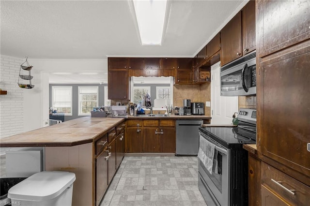 kitchen with dark brown cabinetry, appliances with stainless steel finishes, and sink