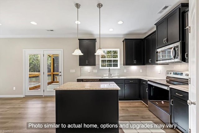kitchen with crown molding, dark cabinets, appliances with stainless steel finishes, and a sink