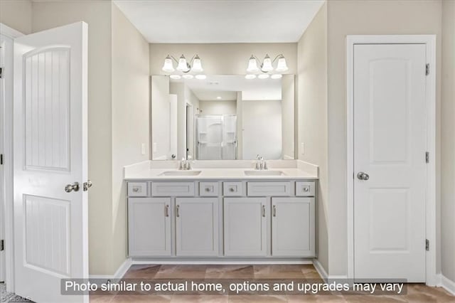 full bath featuring baseboards, a sink, walk in shower, and double vanity