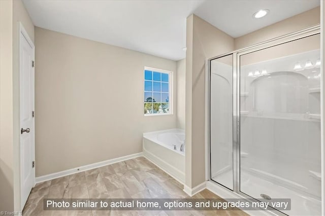 bathroom featuring baseboards, a bath, and a stall shower