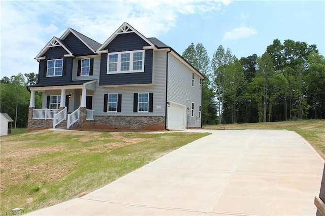 craftsman inspired home featuring covered porch, an attached garage, brick siding, and a front yard