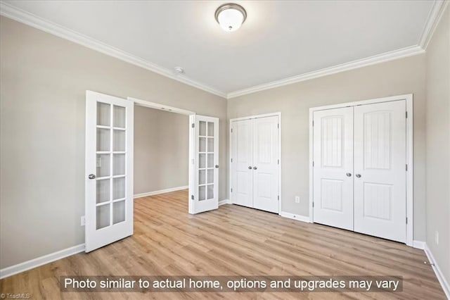 unfurnished bedroom with french doors, ornamental molding, multiple closets, and wood finished floors