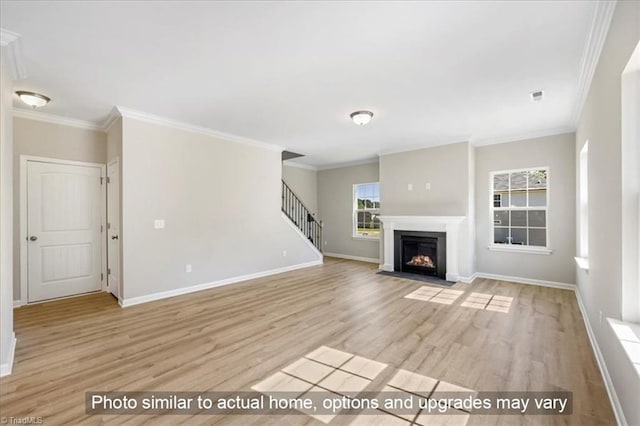 unfurnished living room with baseboards, ornamental molding, light wood-type flooring, and stairs