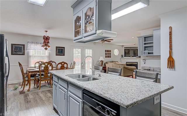 kitchen with gray cabinets, sink, a center island with sink, and light wood-type flooring