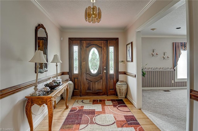 entrance foyer with a wealth of natural light, crown molding, a textured ceiling, and light wood-type flooring