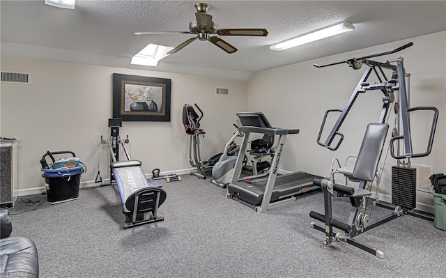 workout area featuring a textured ceiling, a skylight, and ceiling fan