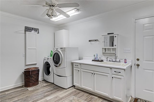 clothes washing area featuring sink, washing machine and clothes dryer, cabinets, ornamental molding, and light hardwood / wood-style flooring