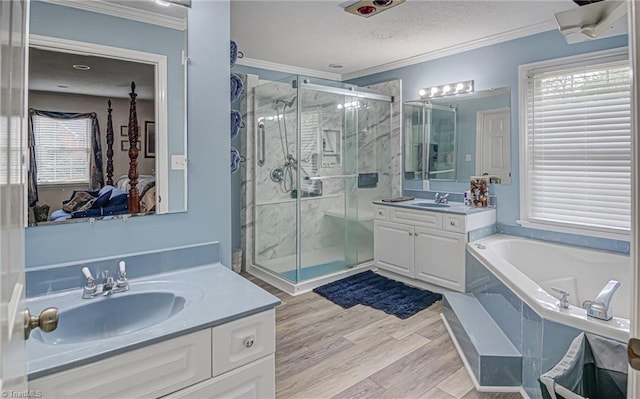 bathroom featuring a textured ceiling, separate shower and tub, vanity, hardwood / wood-style flooring, and ornamental molding