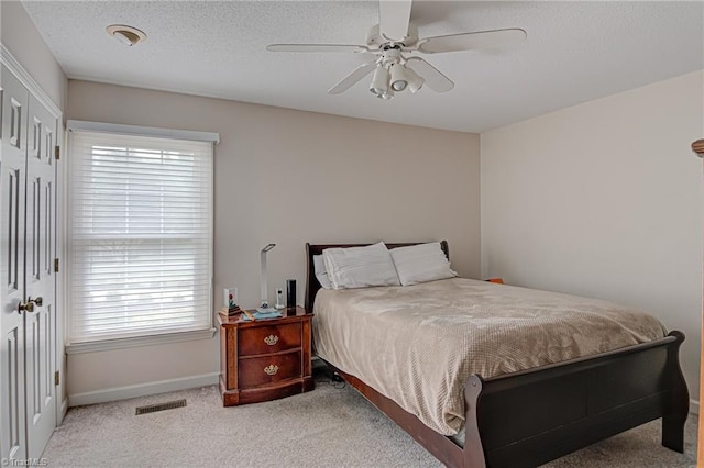 carpeted bedroom featuring a textured ceiling, a closet, and ceiling fan