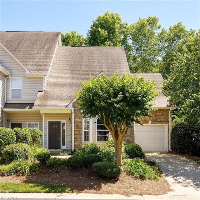 3820 Wayfarer Dr, Greensboro, NC 27410 - view of front of property featuring driveway, an attached garage, a shingled roof, and stone siding