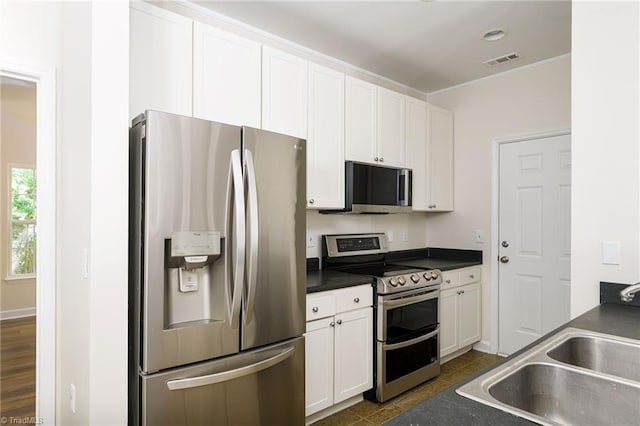 3820 Wayfarer Dr, Greensboro, NC 27410 - kitchen featuring appliances with stainless steel finishes, a sink, dark countertops, white cabinetry, and crown molding