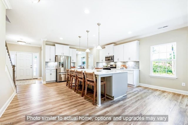 kitchen featuring stainless steel appliances, crown molding, light wood-style flooring, a breakfast bar area, and backsplash