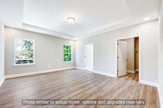 unfurnished room featuring a tray ceiling, wood finished floors, baseboards, and recessed lighting
