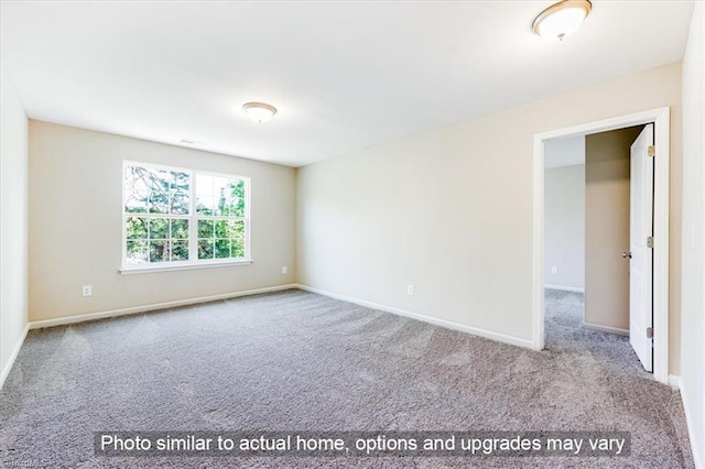 carpeted empty room featuring baseboards