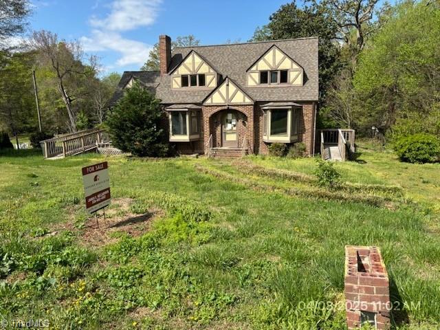 120 Harmon Dr, Thomasville, NC 27360 - tudor home with roof with shingles, a front yard, brick siding, and a chimney