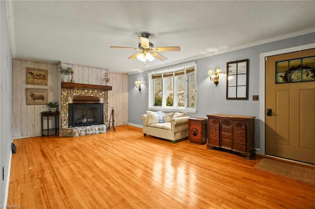 living area with a fireplace, a textured ceiling, crown molding, and hardwood / wood-style flooring