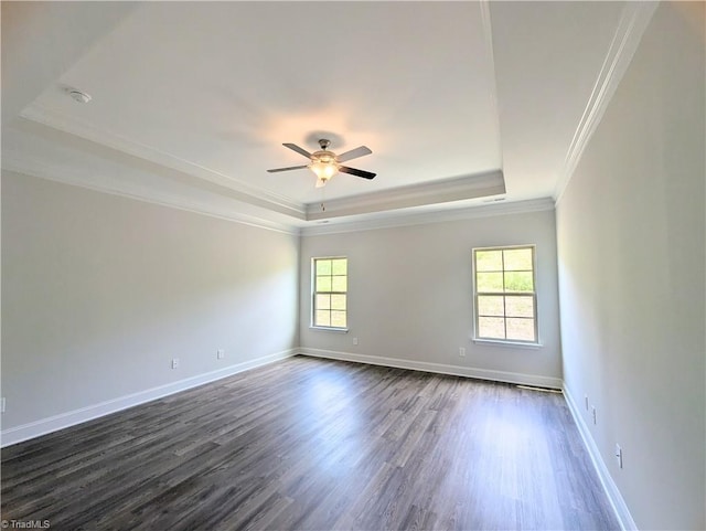 empty room with ceiling fan, dark wood-type flooring, a tray ceiling, and ornamental molding