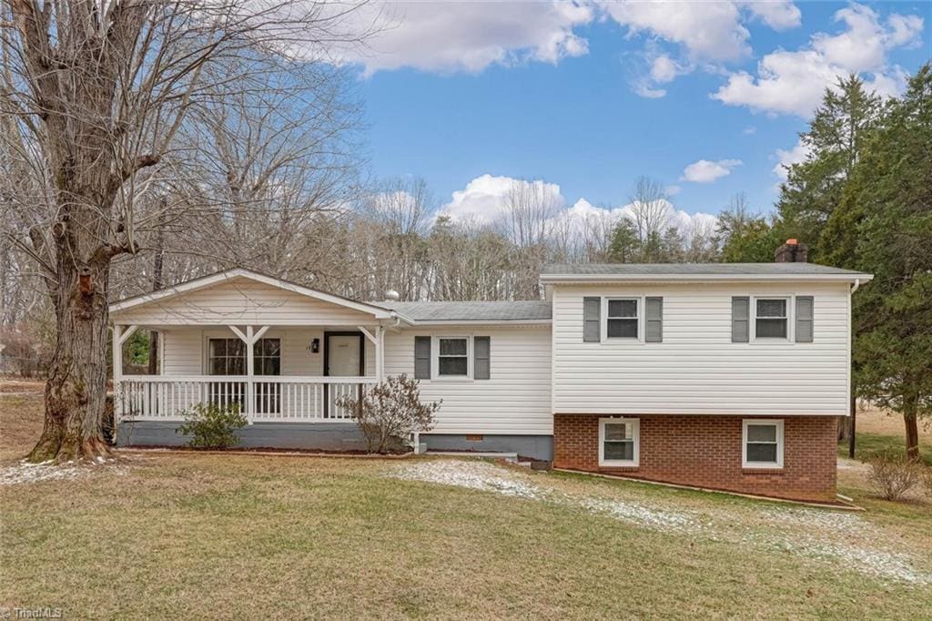 rear view of house featuring a lawn and covered porch