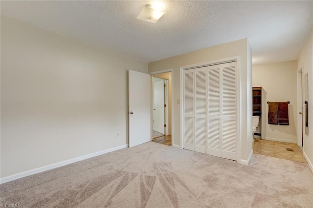 unfurnished bedroom featuring light carpet, a textured ceiling, and a closet