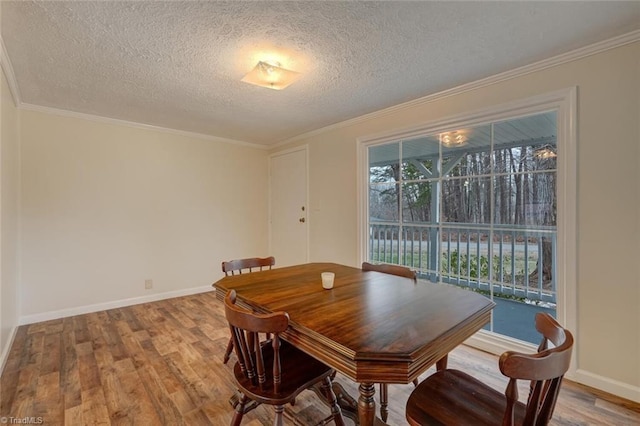 dining space with hardwood / wood-style floors, a textured ceiling, and ornamental molding