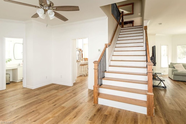 stairs featuring ornamental molding, hardwood / wood-style floors, and ceiling fan